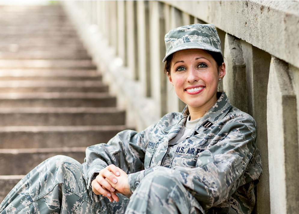 female USAF service member in uniform sitting outside on concrete steps